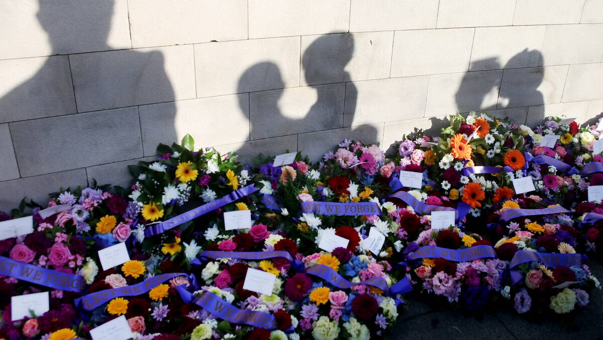 Floral tributes lay against the memorial wall at last year's Anzac Day service in Shellharbour City. 