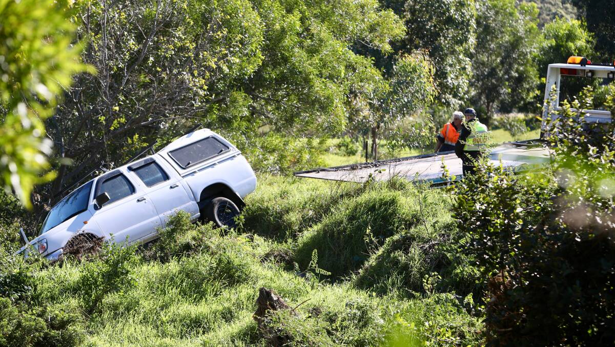 A tow truck works to remove a car from a creek in Figtree on Thursday. Picture: Adam McLean Inset: Darren Butler 
