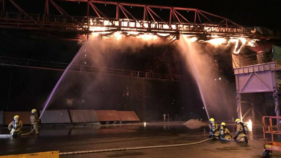 Firefighters train hoses on a conveyor belt attached to the Iron Chieftain, in the early stages of the firefighting effort last June. Picture: Supplied