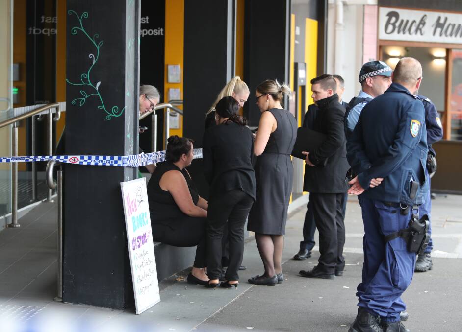 Staff comfort one another outside the cordoned-off bank, before departing together to the cafe next door.  