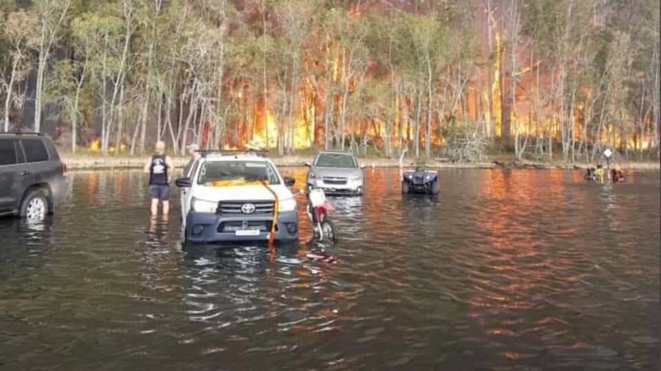 Conjola Park residents drive into the lake as the bushfire razes the town. Photo: Leigh Stewart, Facebook