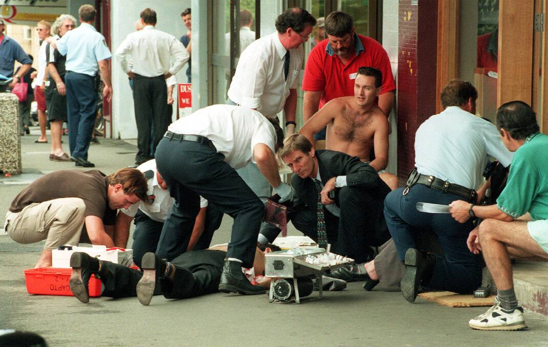 Ambulance officers tend to a wounded man after the fatal shooting in front of the Monsoon restaurant. June 16, 2000.  
