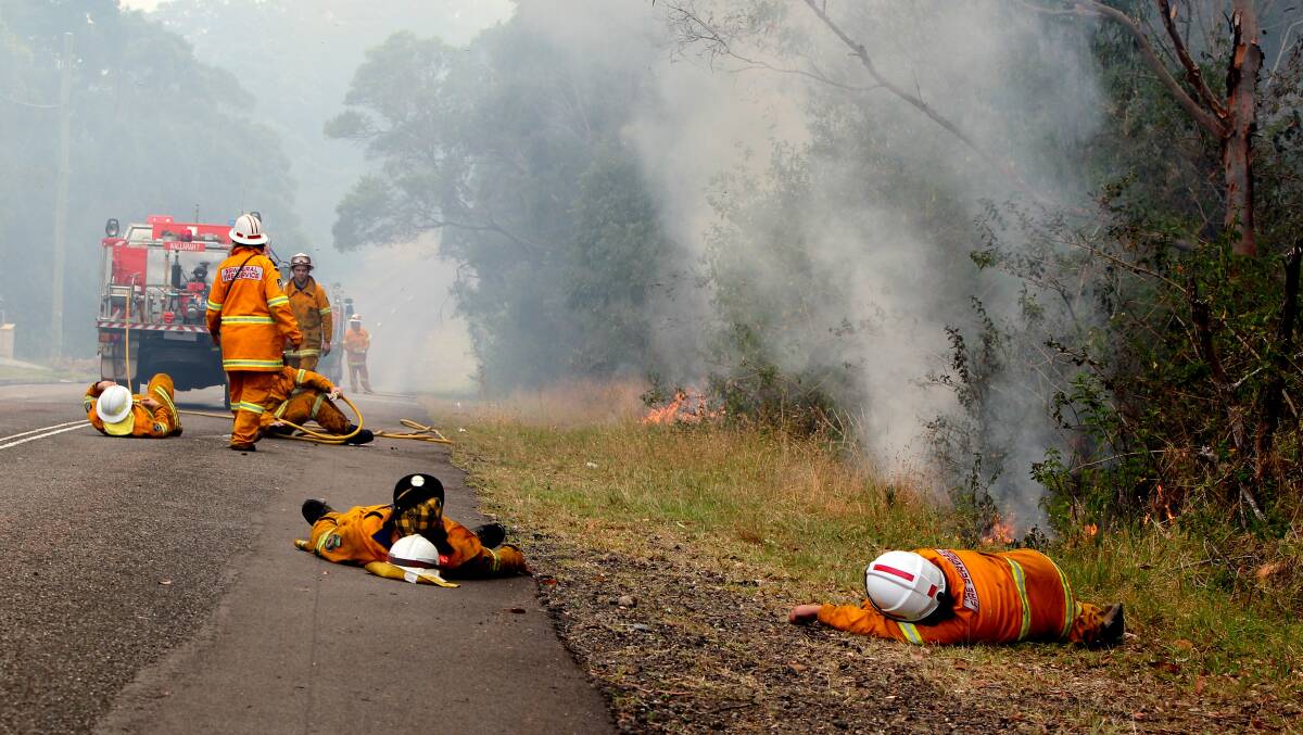 Exhausted firefighters have a rest on Cragan Bay Road at Nords Wharf during October 2013 bushfires. Photo: Phil Hearne