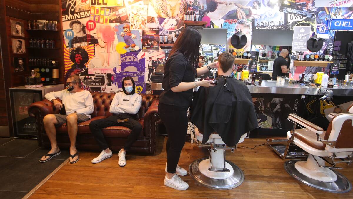 Men wait to get their hair cut at Moe & Co in Stockland Shellharbour on Monday. Photo: Sylvia Liber
