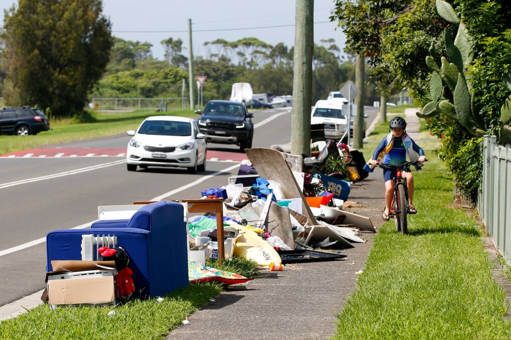 Dumped: A child cycles down the footpath, dodging piles of rubbish. Picture: Anna Warr