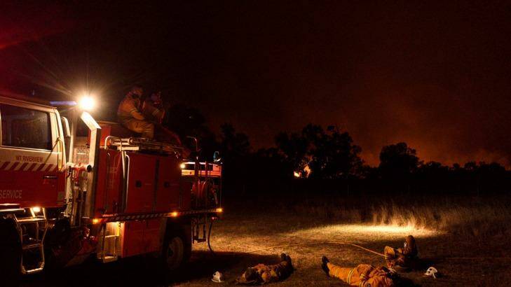 NSW RFS crew members from Cumberland Strike Team take a well earned rest after a long day of fighting a large grass fire burning towards the small township of Wollar in the greater Hunter region. Photo: Wolter Peeters