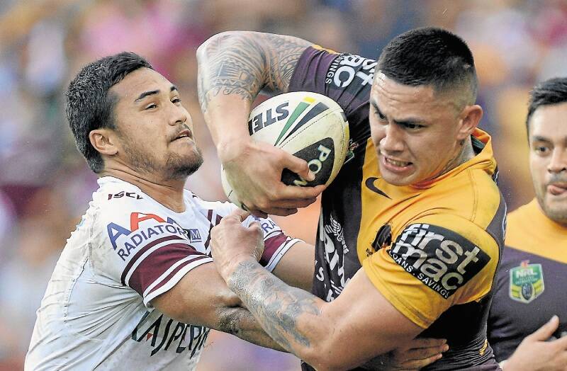 Daniel Vidot tries to brush off Manly tackler Peta Hiku at Suncorp Stadium on Sunday. Picture: GETTY IMAGES