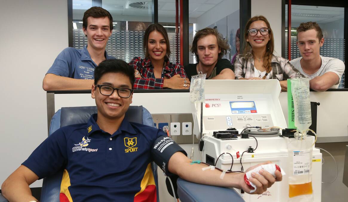University of Wollongong students Martin Serrano (sitting) and Todd Roberts, Nicki Emery, Joel Reynolds, Stephanie Dias and Sam Malcolm donate blood as part of a challenge. Picture: KIRK GILMOUR