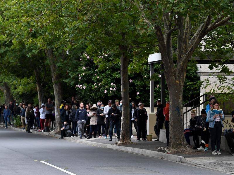 People wait in line at a Centrelink office in Melbourne to register for JobSeeker.