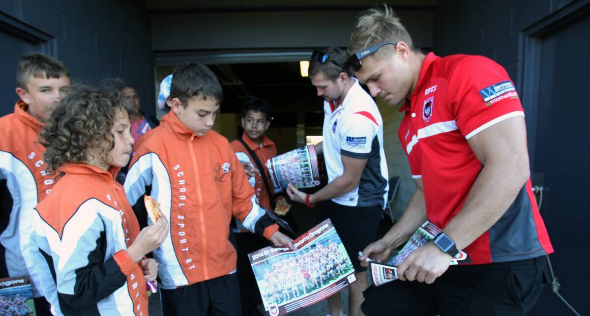 Dragons fans Jake Butler, left, and Josh Morris, both 12, have autographs signed by Will Matthews and Jack de Belin on Wednesday. Picture: GREG TOTMAN