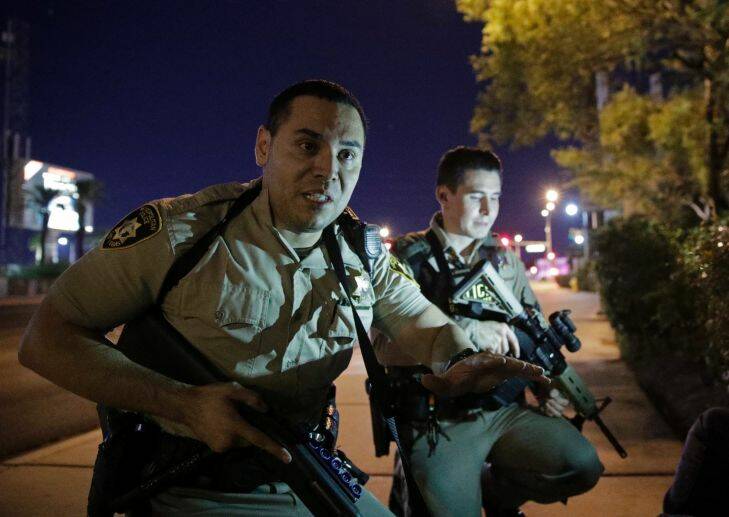 Police officers advise people to take cover near the scene of a shooting near the Mandalay Bay resort and casino on the Las Vegas Strip. Picture: AP