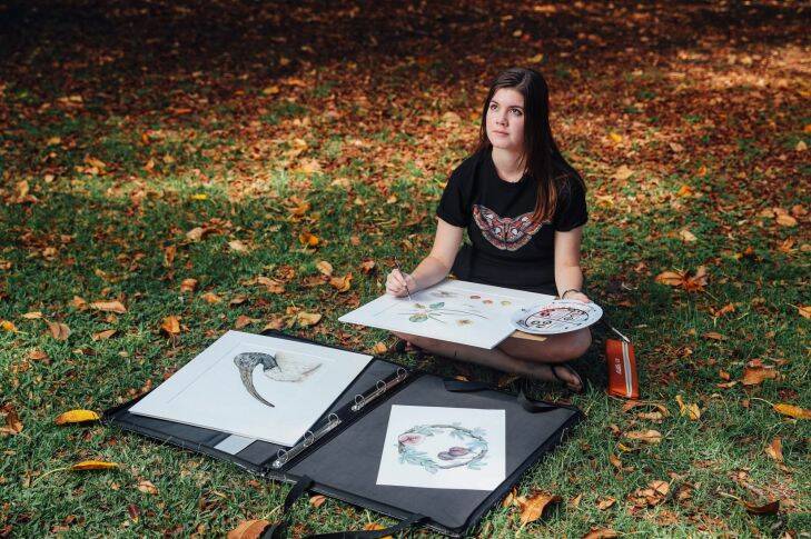 Samantha Bayly poses for a photograph surrounded by her work and wearing one her prints on a t-shirt. Samantha studies Natural History Illustration at the University of Newcastle and is one of two recipients of a new $10,000 scholarship inspired by the 19th century scientific illustrations of Harriet and Helena Scott.