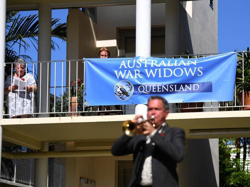 War widows watch Alastair Tomkins play during a small Anzac Day ceremony in Brisbane.