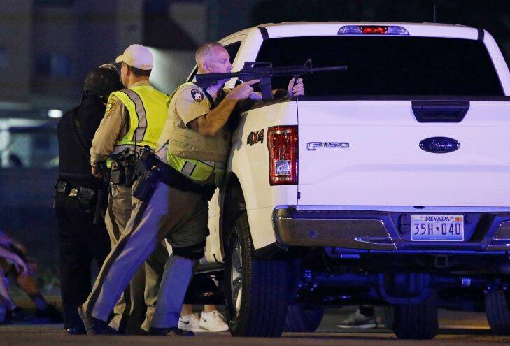 A police officer takes cover behind a truck at the scene of a shooting near the Mandalay Bay resort and casino on the Las Vegas Strip. Picture: AP