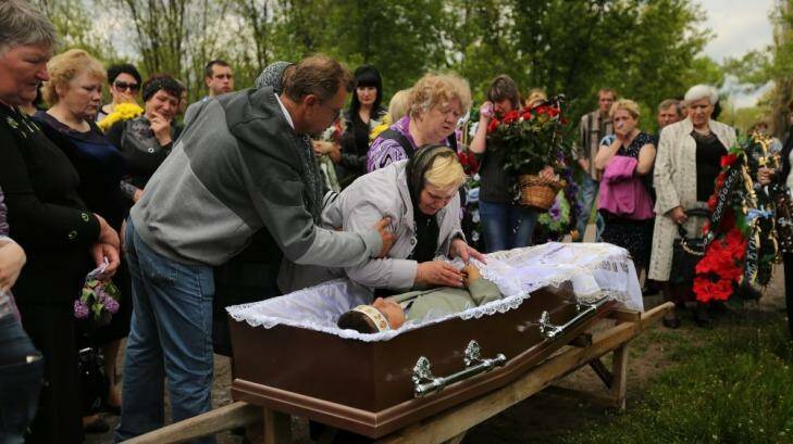 The mother of 39-year-old miner, Vadim Hudich, embraces her son in a final goodbye during his funeral.  Photo: Kate Geraghty
