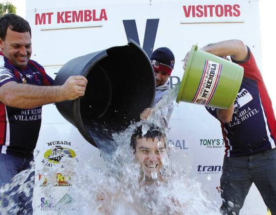 Mt Kembla Lowries players Dale Lund, Dale Laidlaw and Ryan Egan douse Brenton Nobbs in icy water as part of a challenge for charity. Picture: GREG TOTMAN