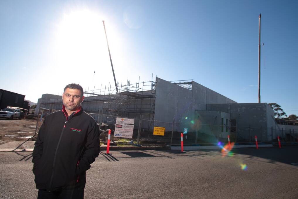 Bulli Fruit and Deli owner Gary Mustafa in front of the Woolworths store being built in Molloy Street. He wants residents to support local independent retailers. Picture: ADAM McLEAN