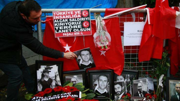 A man adjusts a victim's photograph displayed with floral tributes and Turkish flags outside the Reina night club following the New Year's Day attack in Istanbul. Photo: Emrah Gurel