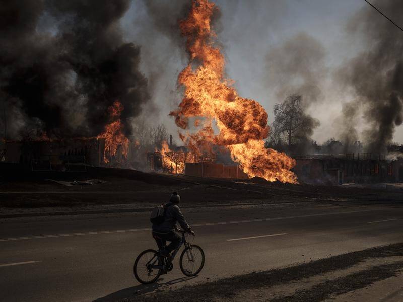 A man rides his bike past burning buildings following a Russian attack in Kharkiv, Ukraine.