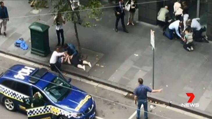 An image of Henry Dow and the taxi driver known as 'Lou' caring for a victim of the Bourke Street attack on Friday. Photo: Courtesy: Seven News Melbourne