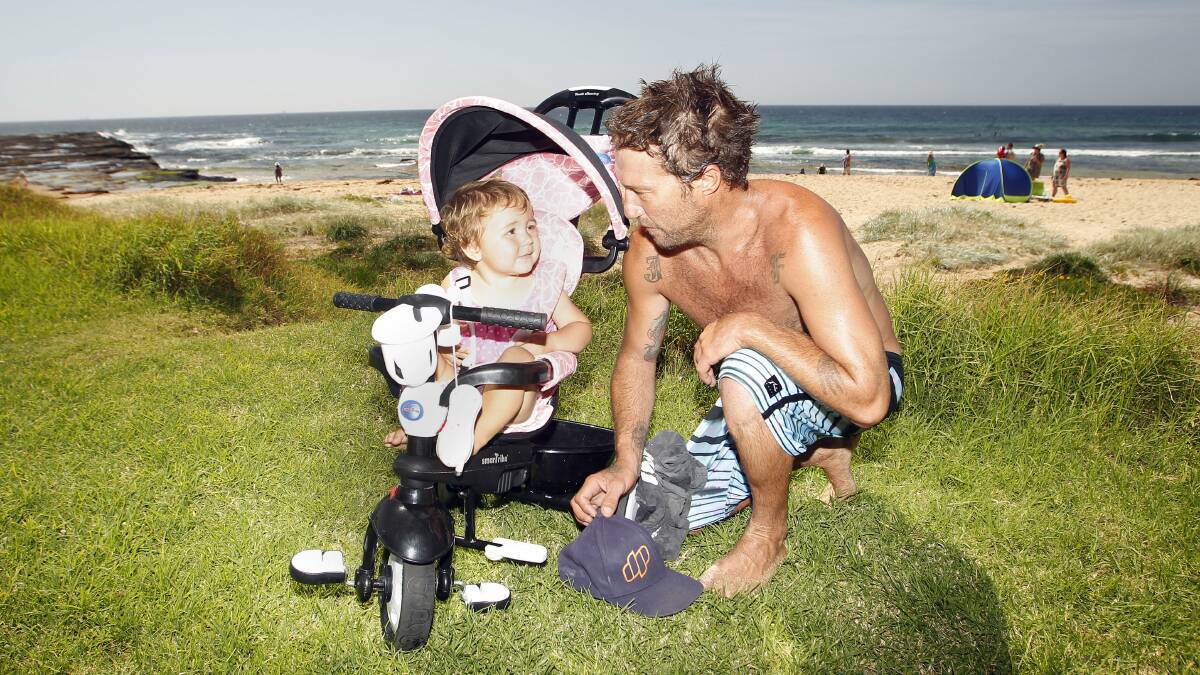 Joel Forbes, of Coledale, and daughter Alyssa, 1, soak up the New Year sunshine at Austinmer Beach.  Pictures: ANDY ZAKELI