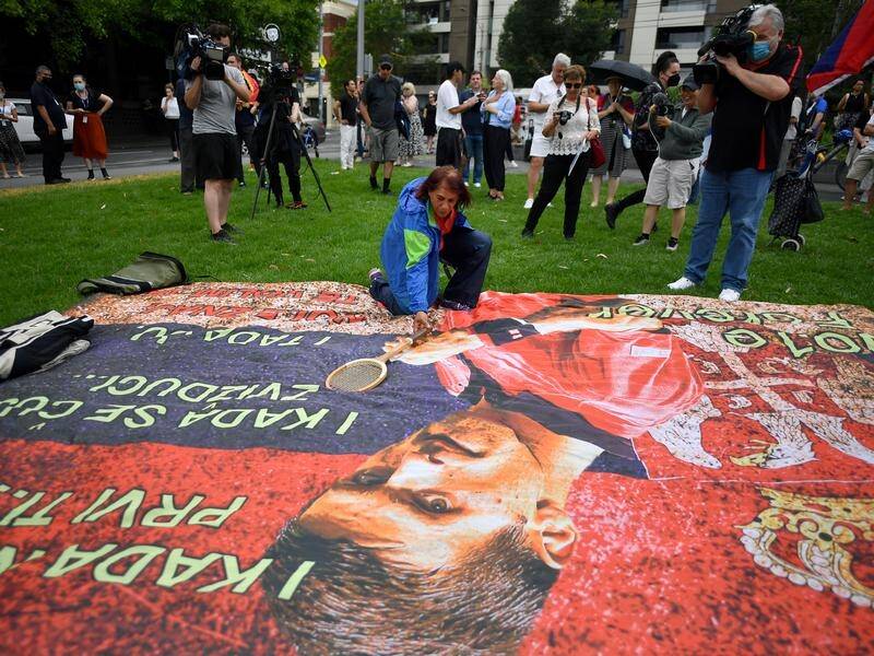 Protesters outside an immigration hotel have unfurled a banner featuring Novak Djokovic's portrait.