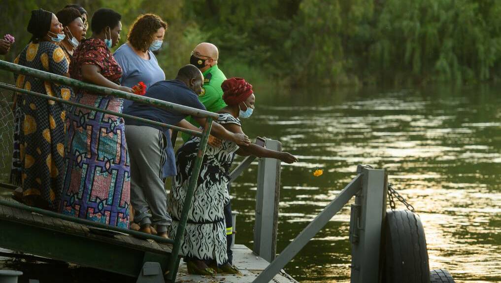 Members of the Congolese community throw flowers into the Murray River at a vigil for Julius Lunanga. The Border Mail attended the vigil with permission from the family. Picture: MARK JESSER