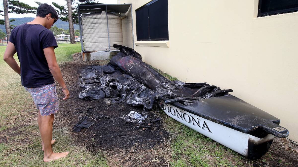 Nick Morgan looks at the burnt out surf boat at the Woonona surf club. Picture: KIRK GILMOUR 