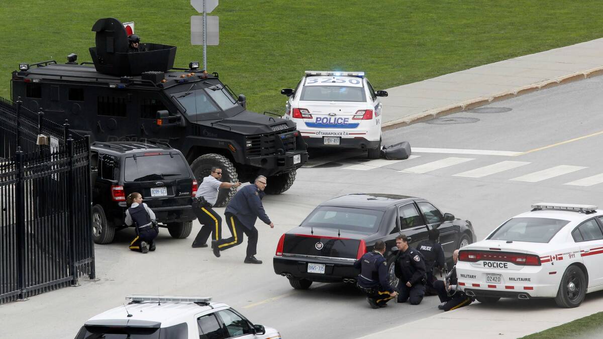 Police officers take cover near Parliament Hilll following a shooting incident in Ottawa. Picture: REUTERS