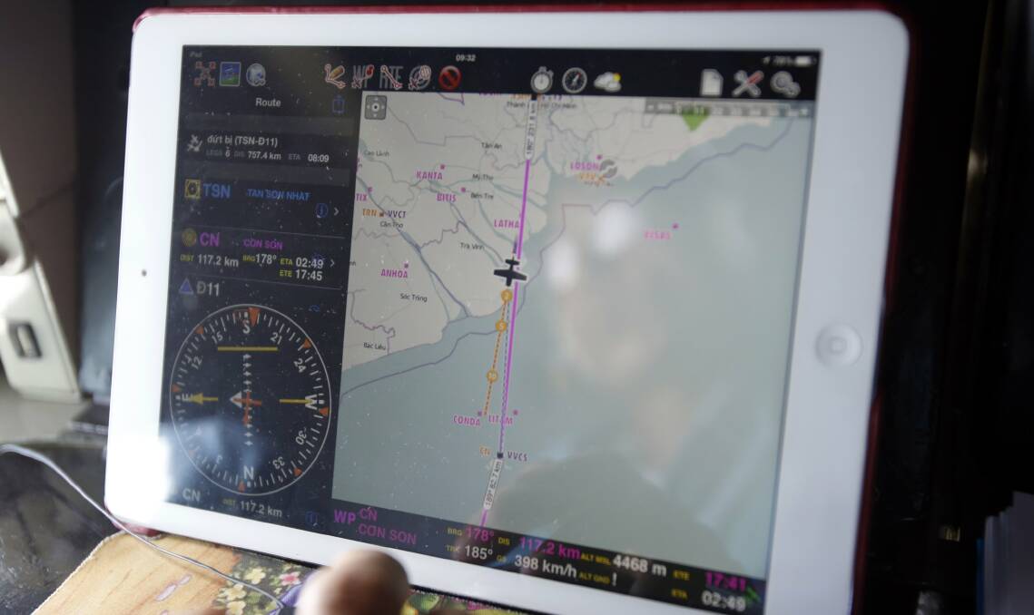 The search continues ... Military officer Ngo Ngoc Dong is seen reflected in a map on an iPad showing the path of the Vietnam Air Force search and rescue AN-26 aircraft. Picture: REUTERS
