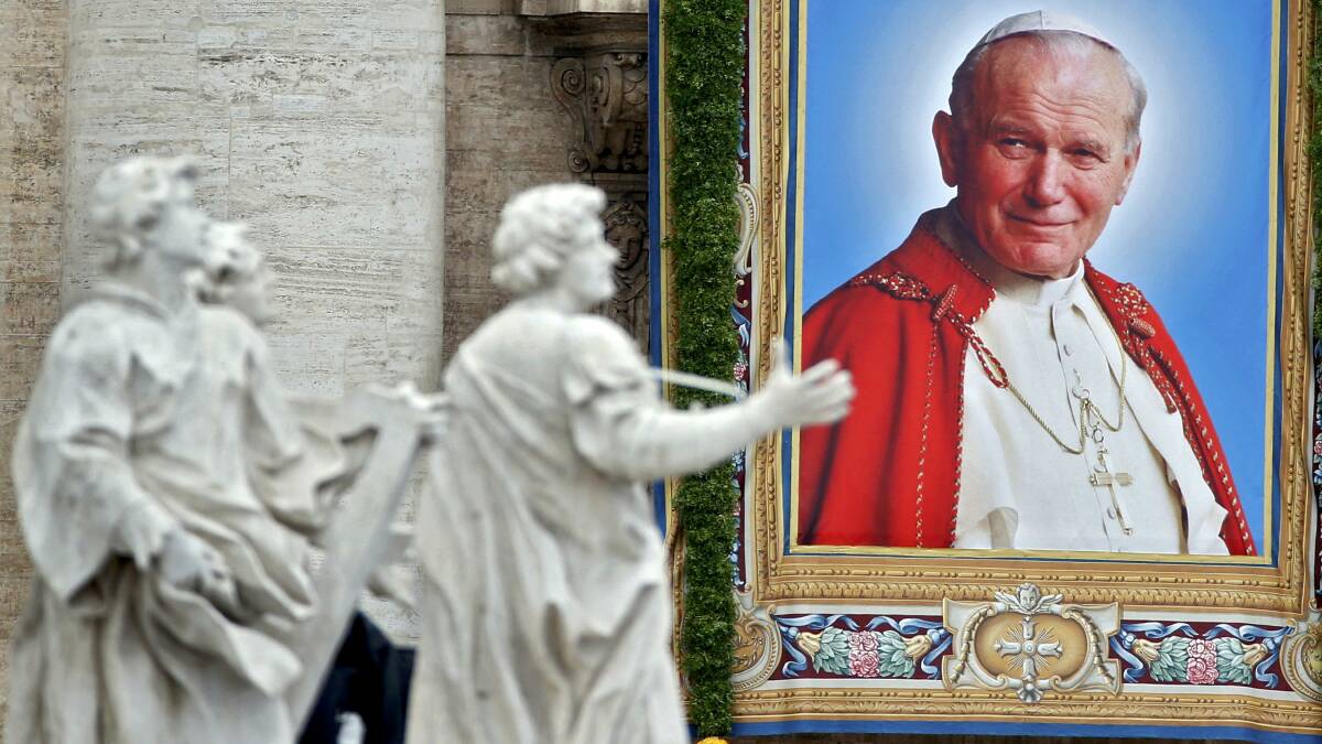 A tapestry portrait of Pope John Paul II hanging from the facade of St Peter's Basilica. Picture: REUTERS
