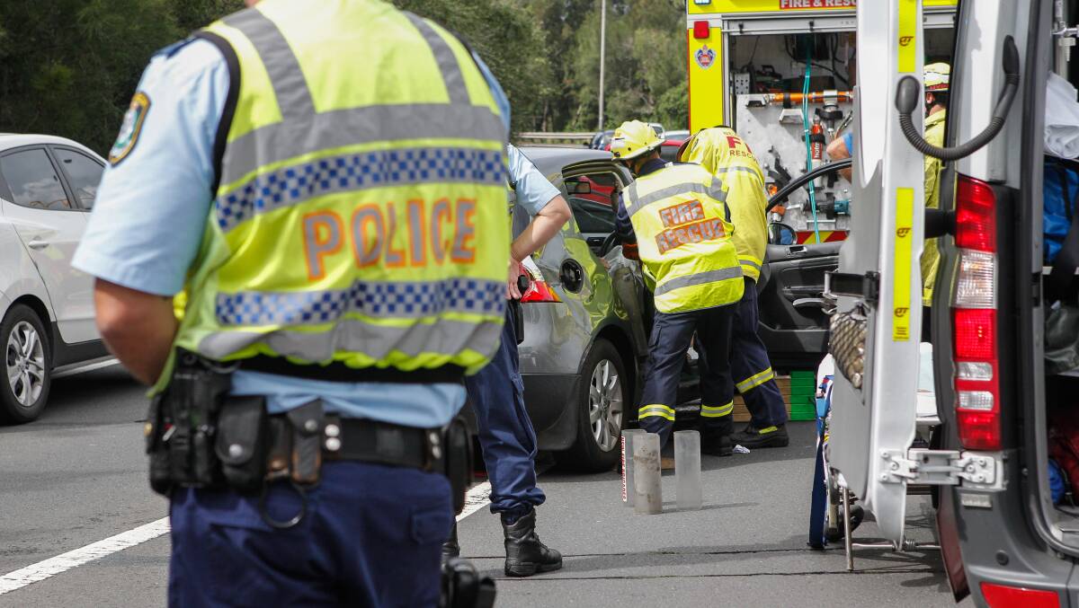 Emergency crews work to free a woman trapped in her car at Figtree on Tuesday. Picture: CHRISTOPHER CHAN.