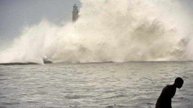 A man walks on a sea wall as the ocean crashes into el Morro light house, after the passing of Hurricane Irma in Havana, Cuba. Photo: AP
