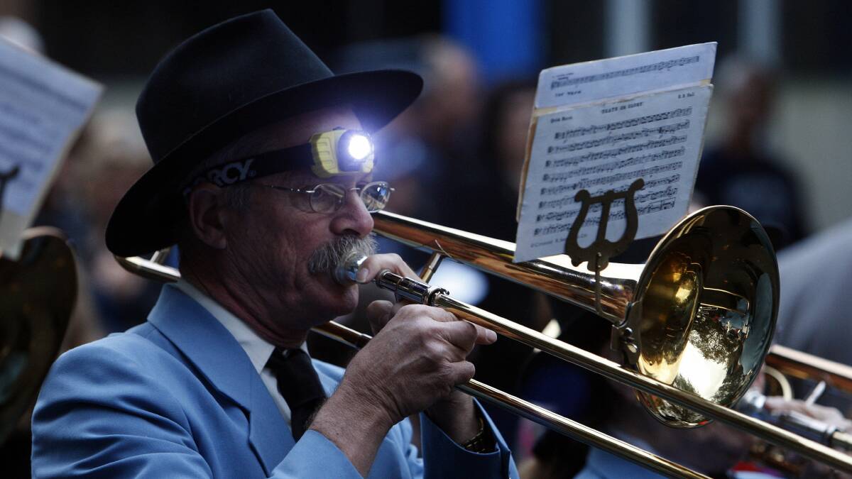 Wollongong City Brass Band trombone player Lyndsay Dunstan lights up his music sheet during the Port Kembla dawn service. Picture: ANDY ZAKELI