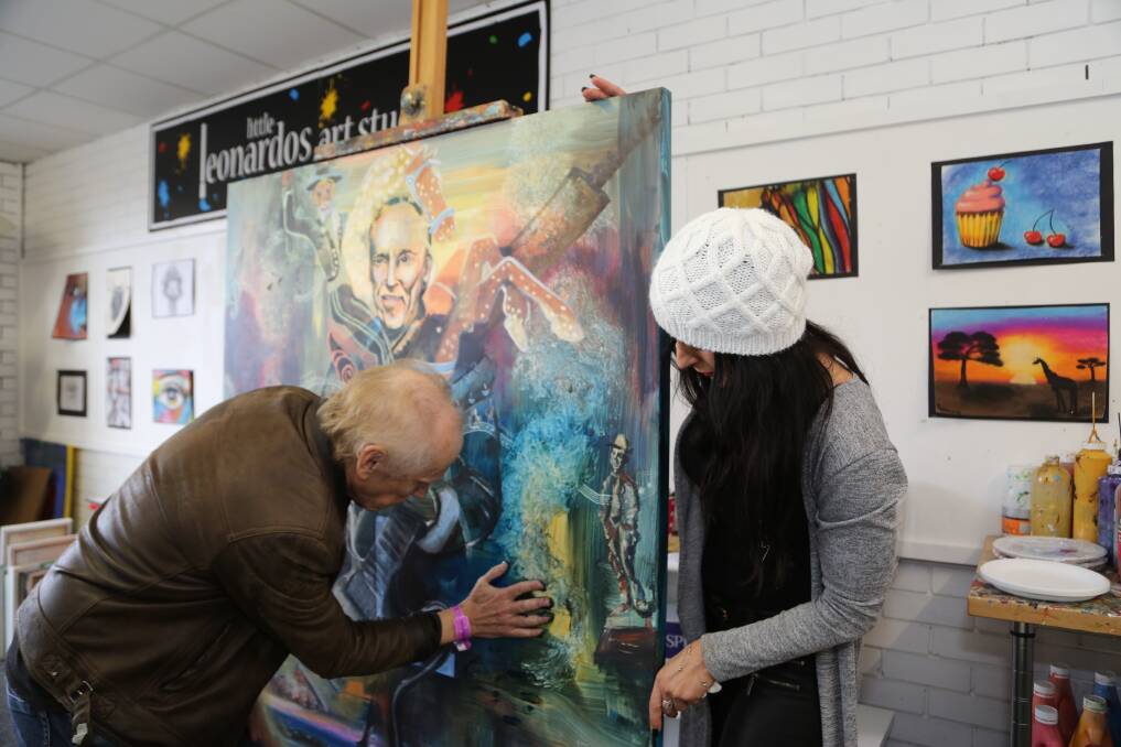 Natalija Vocanec looks on as musician Graham Wilson (left) puts his hand print on an artwork that is going to be auctioned on Tuesday night to help cover his ongoing medical expenses as he continues his fight with brain cancer. Picture: GREG ELLIS