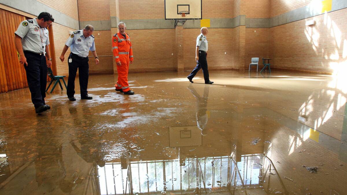 Emergency workers look at flooded areas of Bulli High School on March 25. Picture: KIRK GILMOUR