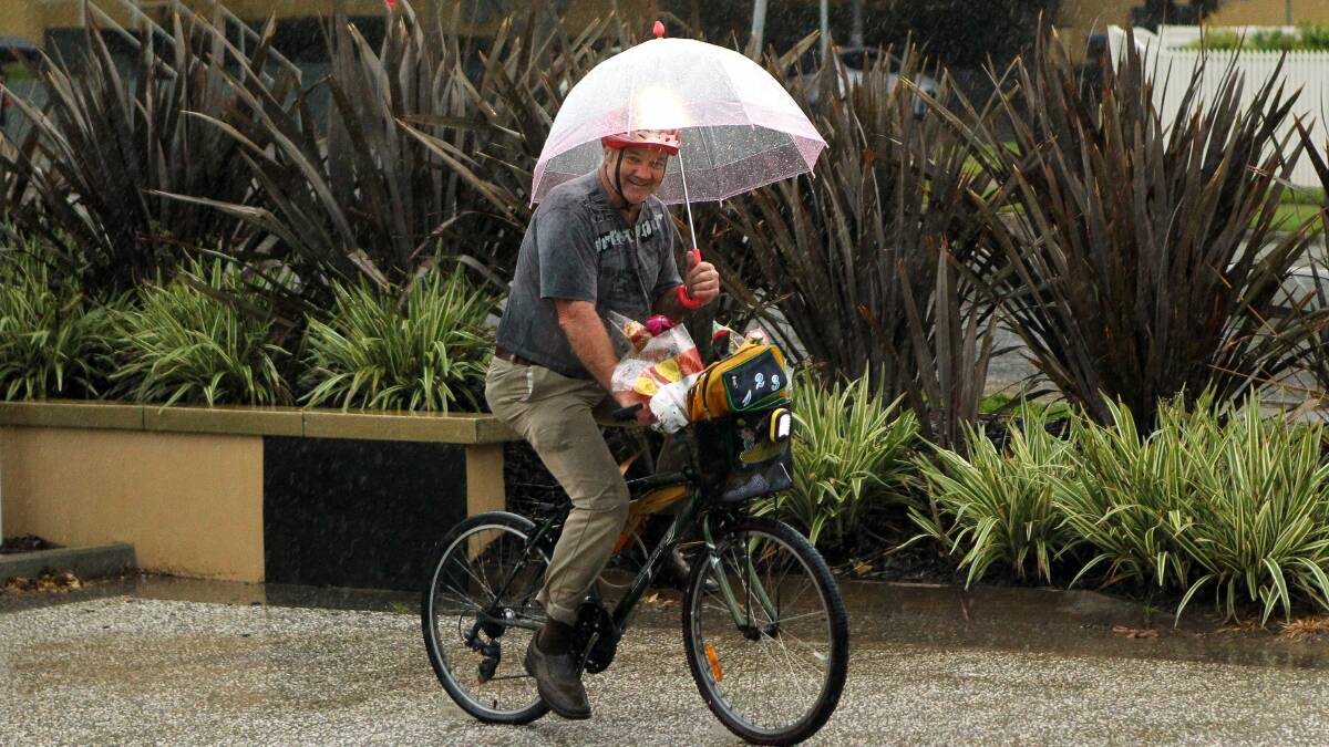 John Pink armed himself with an umbrella to cycle along the bike track at North Wollongong. Picture: KIRK GILMOUR