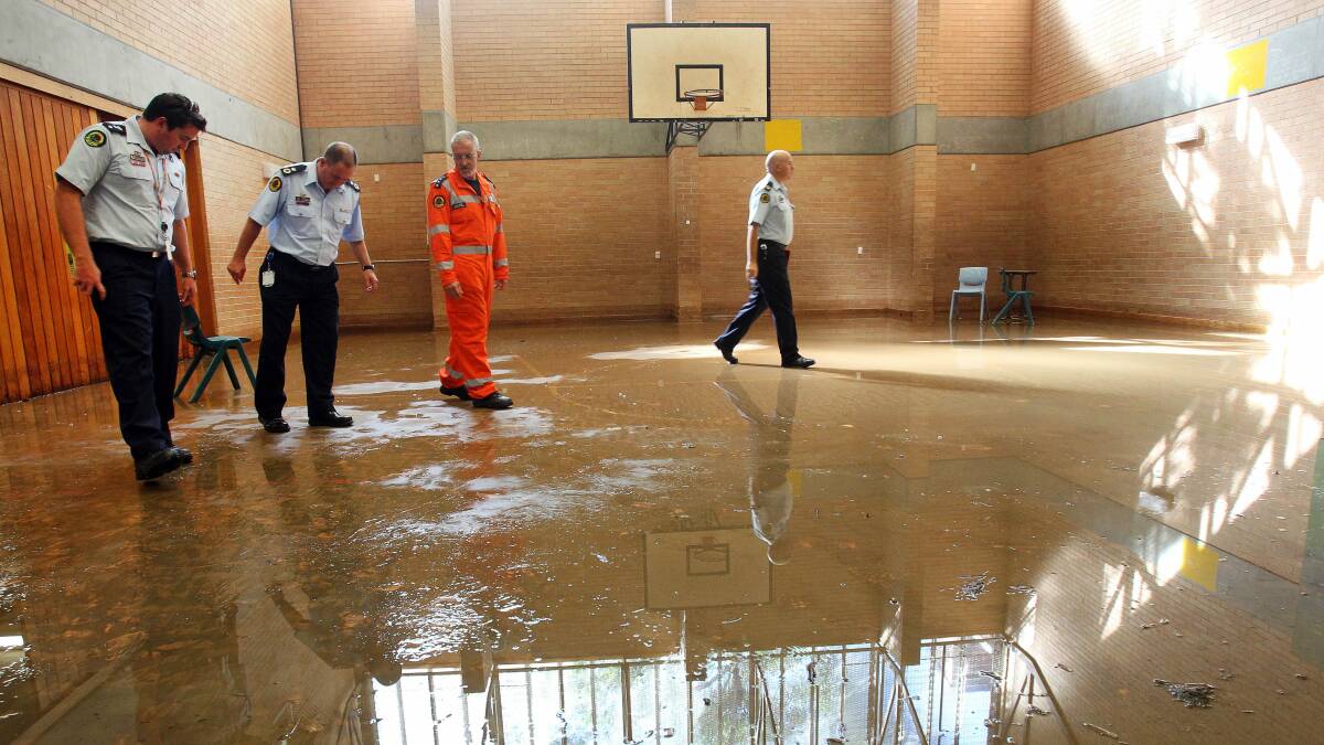 Emergency services workers walk over the flooded basketball court at Bulli High School last month.