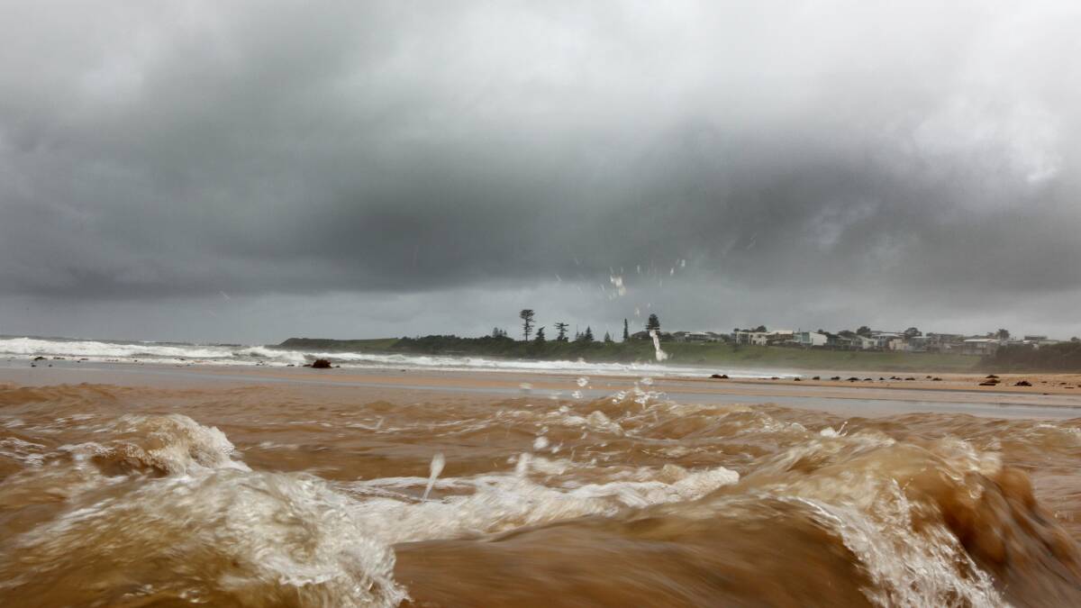 Muddy water from Hewitts Creek empties into McCauleys Beach at Thirroul on March 26. Picture: KIRK GILMOUR