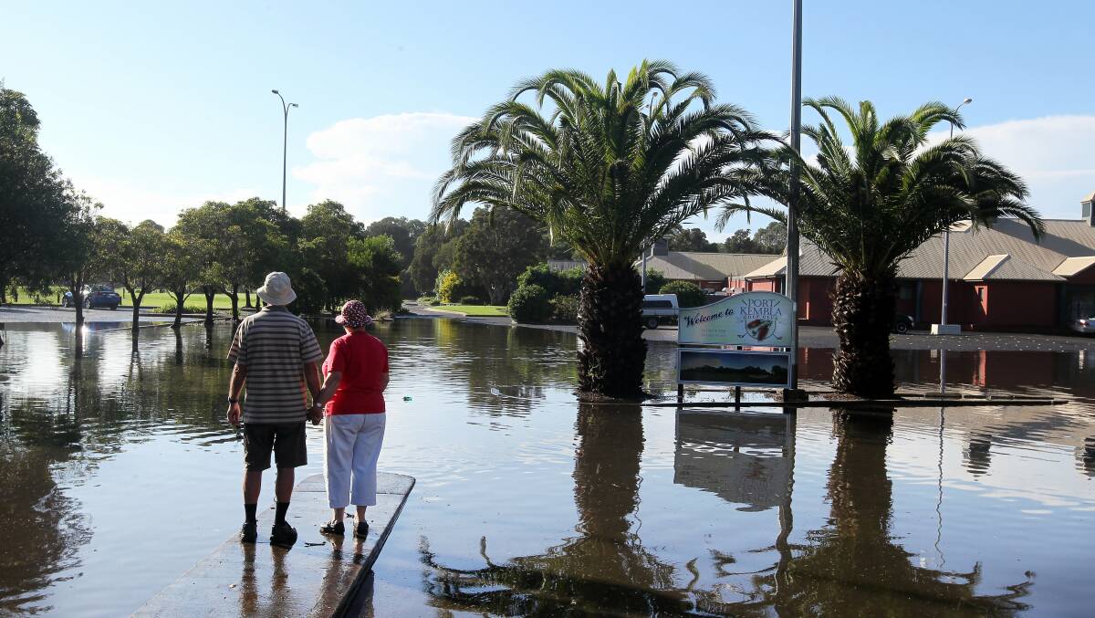 A couple look over the flooded entrance to Port Kembla Golf Club. Picture: SYLVIA LIBER
