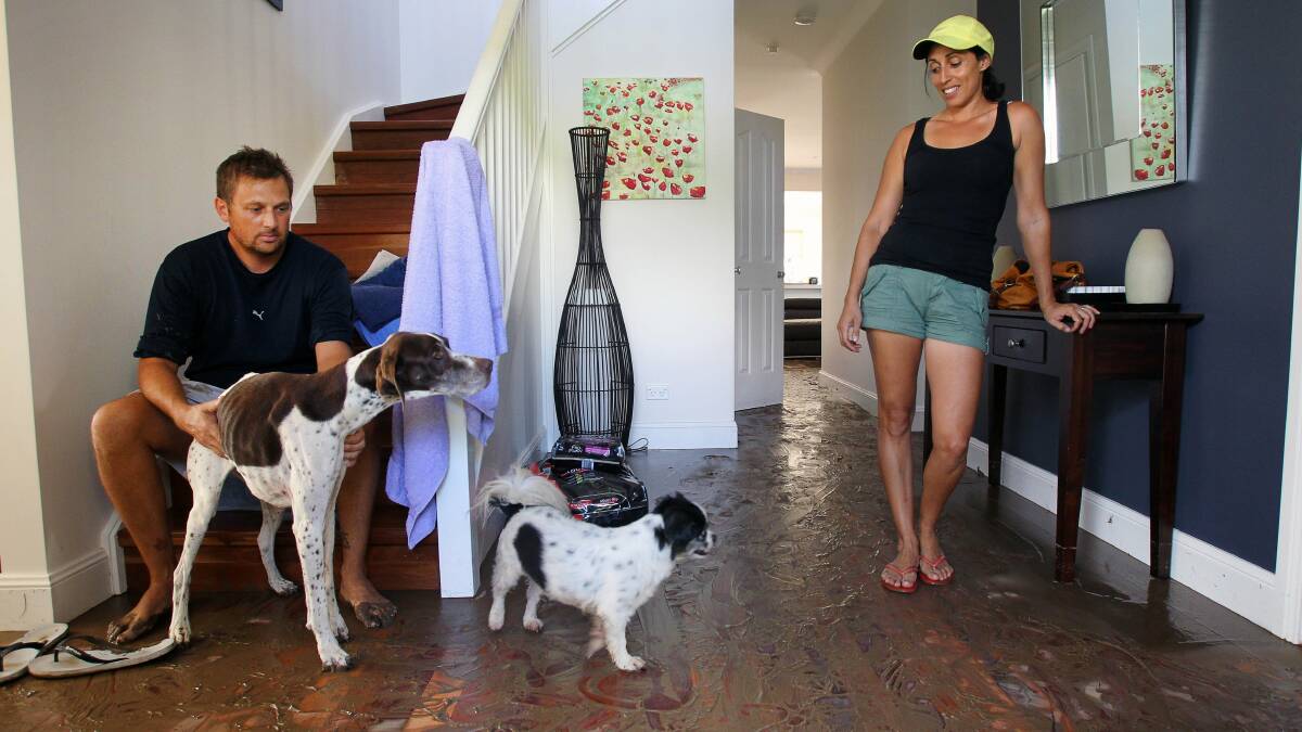 Matthew and Maree Becker with their pet dogs Cana and Mello in their flooded home in Benelong st, Bulli. Picture: KIRK GILMOUR
