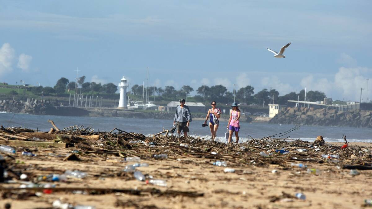 Walkers negotiate debris on the beach at North Wollongong. Picture: SYLVIA LIBER