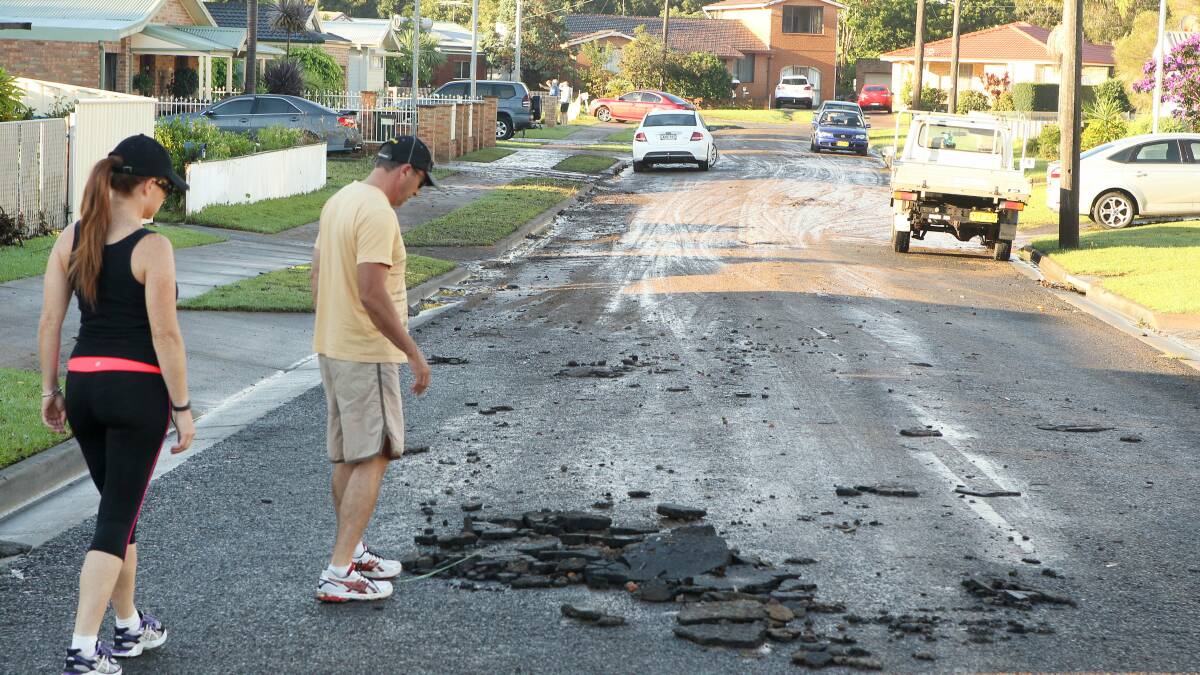 Early morning walkers look at road damage on Benelong St, Bulli, after flooding on March 24. Picture: KIRK GILMOUR