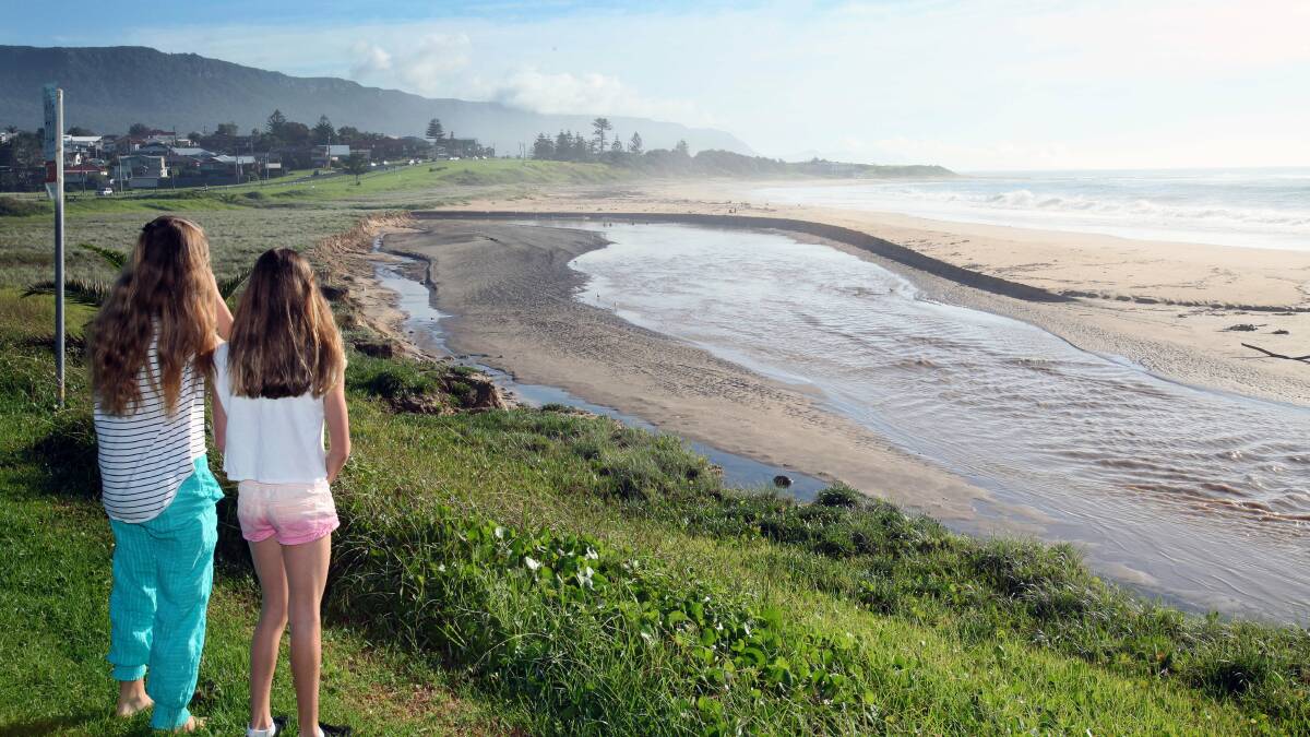 Two girls look at the damage of the flood waters on the beach between Sandon Point and Bulli Beach. Picture: KIRK GILMOUR