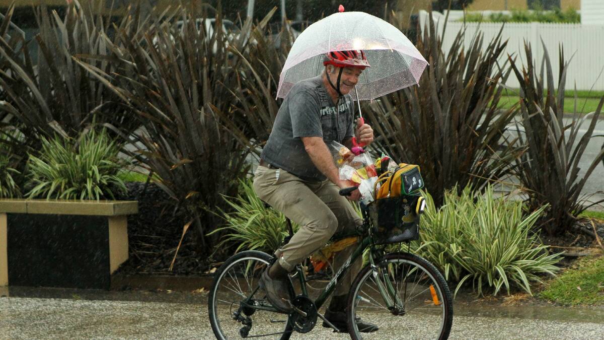 John Pink rides through the rain with the help of an umbrella. Picture: KIRK GILMOUR