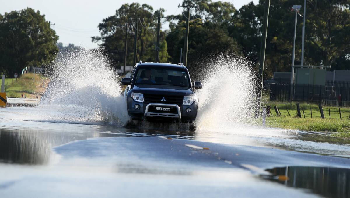 A four-wheel drive travels through water on the Illawarra Highway at Albion Park. Picture: SYLVIA LIBER