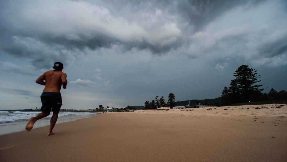 A runner takes to Thirroul Beach on March 7 as storm clouds roll in. Picture: ADAM McLEAN