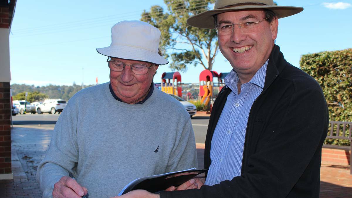 Federal Member for Eden-Monaro Dr Peter Hendy with resident John Carlton signing a petition at Merimbula. Dr Hendy was later attacked by an angry man who tried to punch him.