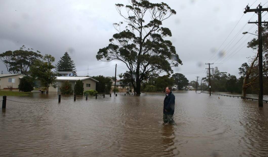 Phil Guy walks through water on Hay Avenue where he lives that runs parallel to the rising Shoalhaven River at Shoalhaven Heads. Picture: KIRK GILMOUR