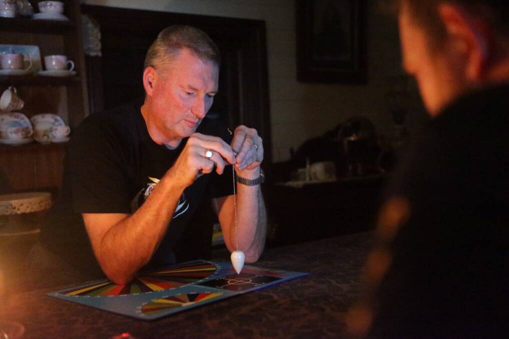 Paranormal investigator Steve Lynch uses a pendulum board to communicate with spirits. Picture: CHRISTOPHER CHAN